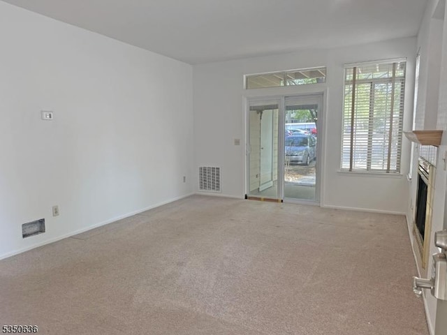 unfurnished living room featuring visible vents, baseboards, a fireplace, and light carpet