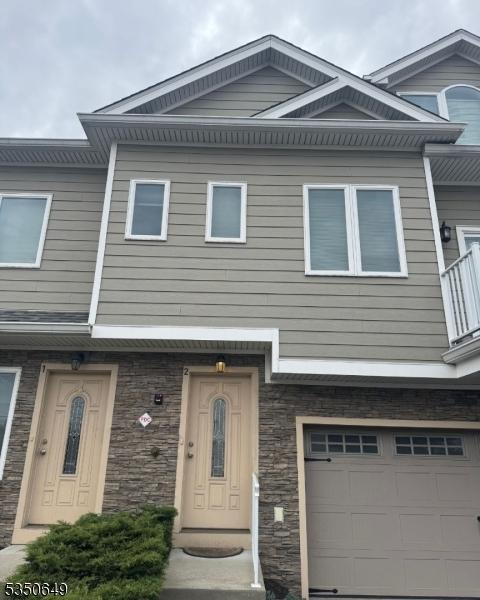 townhome / multi-family property with stone siding and a garage