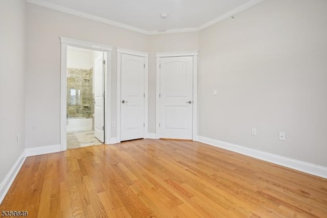 unfurnished bedroom with baseboards, ensuite bathroom, light wood-type flooring, and crown molding