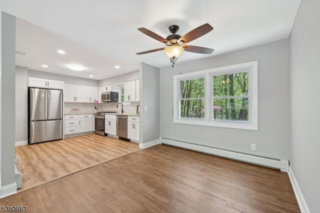 kitchen with white cabinets, ceiling fan, appliances with stainless steel finishes, baseboard heating, and light countertops