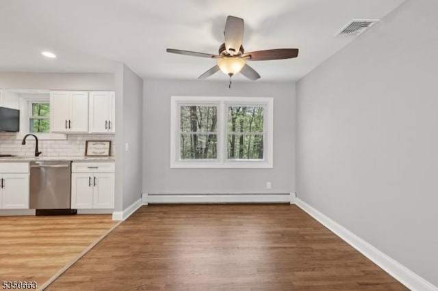 kitchen featuring stainless steel dishwasher, visible vents, white cabinetry, a baseboard heating unit, and backsplash