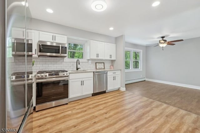 kitchen featuring decorative backsplash, a sink, white cabinets, a ceiling fan, and appliances with stainless steel finishes