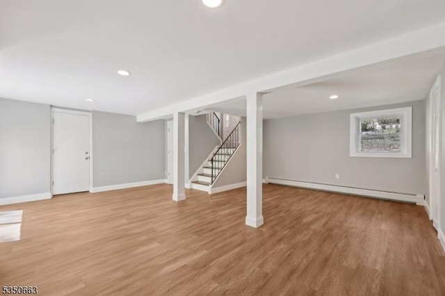 basement featuring light wood-type flooring, stairs, baseboards, a baseboard heating unit, and recessed lighting