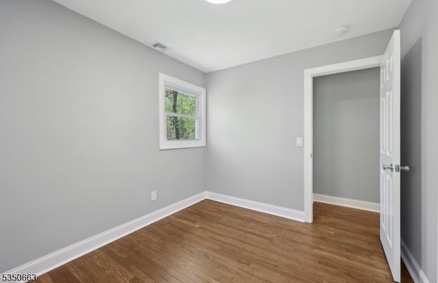unfurnished bedroom with baseboards, visible vents, and wood finished floors