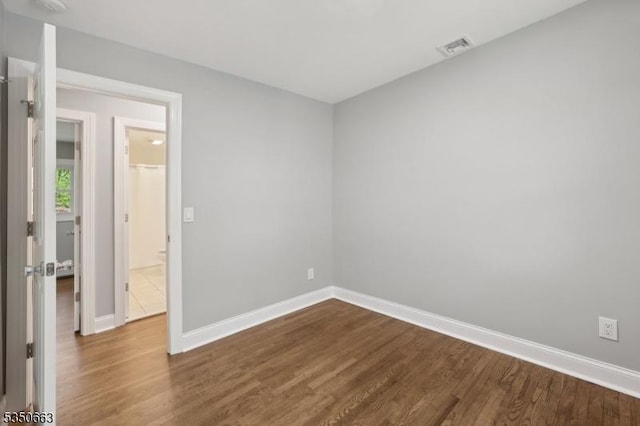 spare room featuring baseboards, dark wood-style flooring, and visible vents