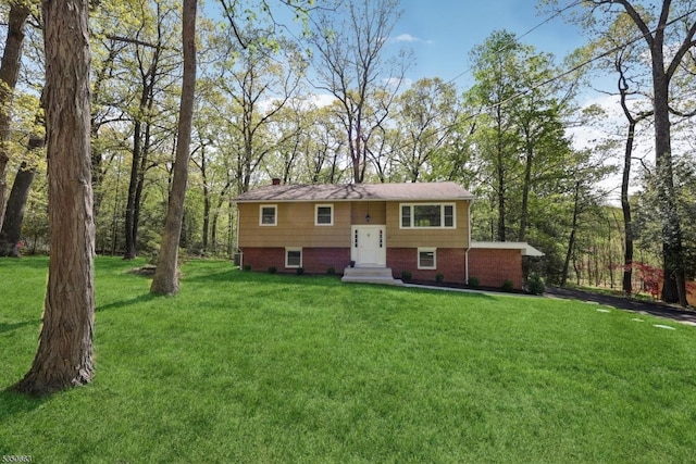 bi-level home with brick siding, a front lawn, and a chimney