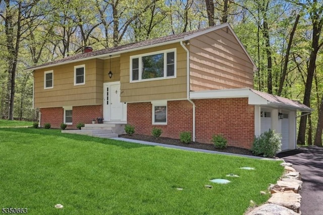 split foyer home with brick siding, a garage, driveway, and a front lawn