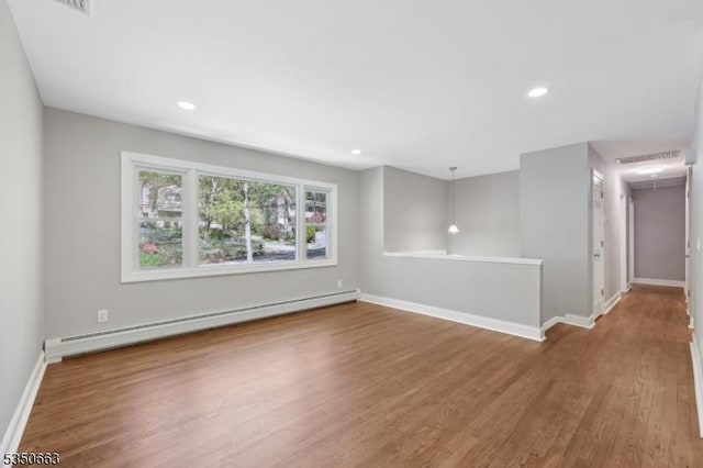 unfurnished room with baseboards, a baseboard radiator, wood finished floors, and recessed lighting