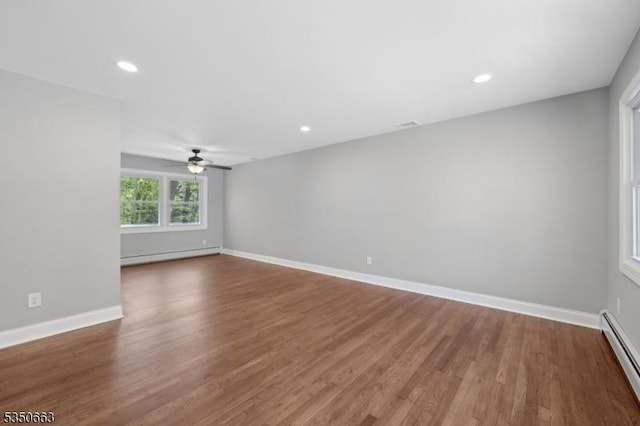 empty room featuring baseboards, a baseboard radiator, a ceiling fan, and wood finished floors