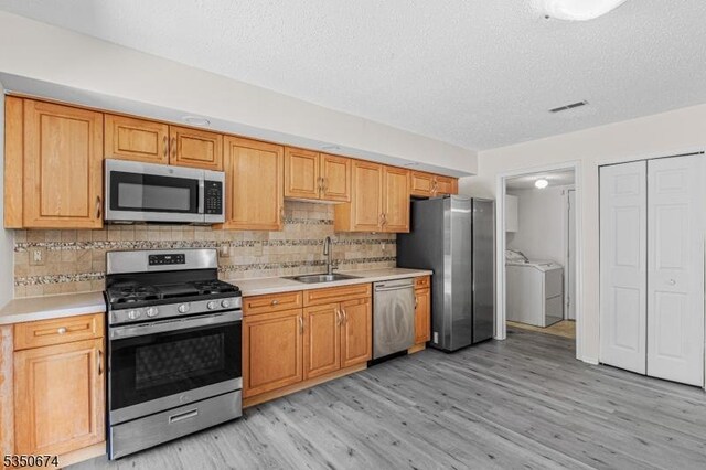 10 Brook St, Franklin Twp, NJ 08873 - kitchen with stainless steel appliances, light countertops, a sink, washing machine and dryer, and a textured ceiling