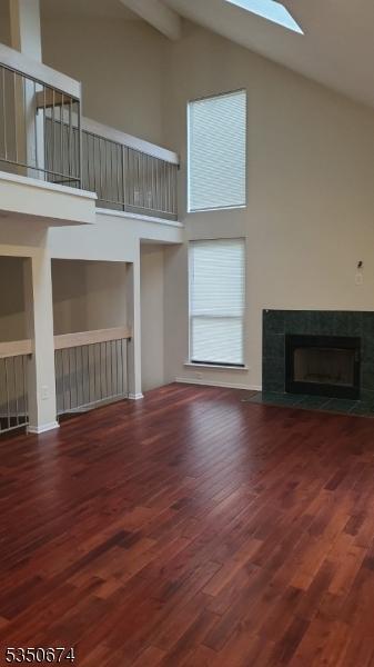 10 Brook St, Franklin Twp, NJ 08873 - unfurnished living room featuring a fireplace, beam ceiling, wood finished floors, a skylight, and high vaulted ceiling