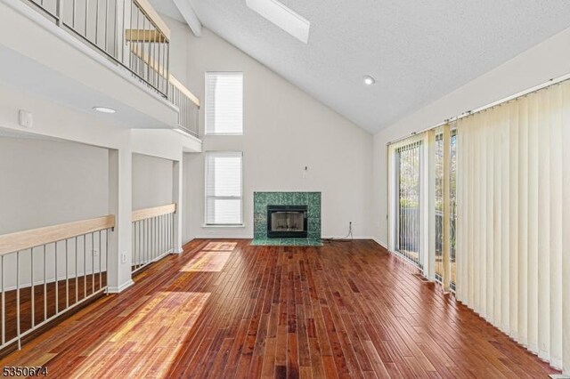 10 Brook St, Franklin Twp, NJ 08873 - unfurnished living room featuring a skylight, a tiled fireplace, high vaulted ceiling, and wood-type flooring