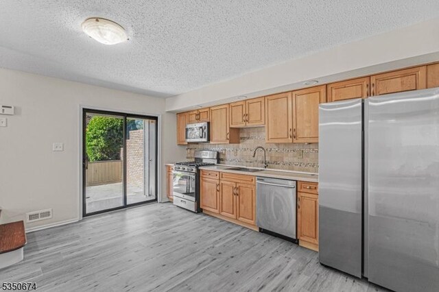 10 Brook St, Franklin Twp, NJ 08873 - kitchen featuring tasteful backsplash, a sink, a textured ceiling, light wood finished floors, and appliances with stainless steel finishes