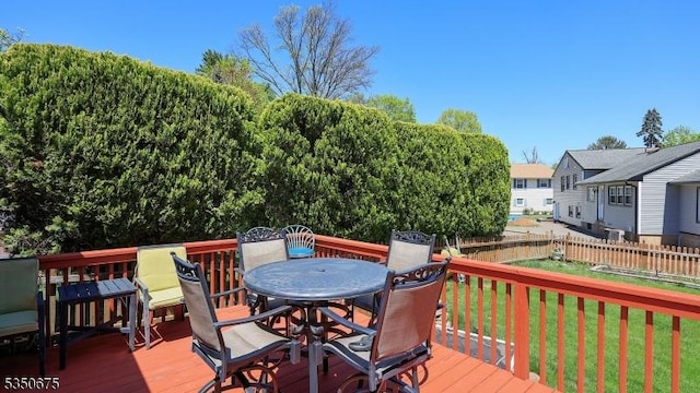 wooden deck with outdoor dining area, a lawn, and fence