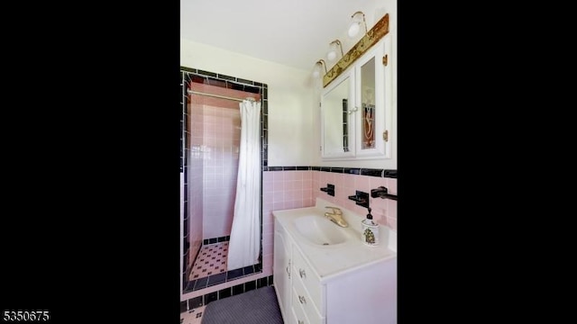 bathroom featuring vanity, tile walls, a wainscoted wall, tile patterned floors, and a shower stall
