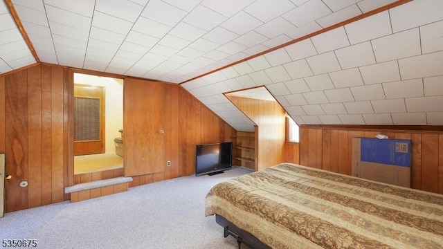 carpeted bedroom featuring wooden walls and vaulted ceiling