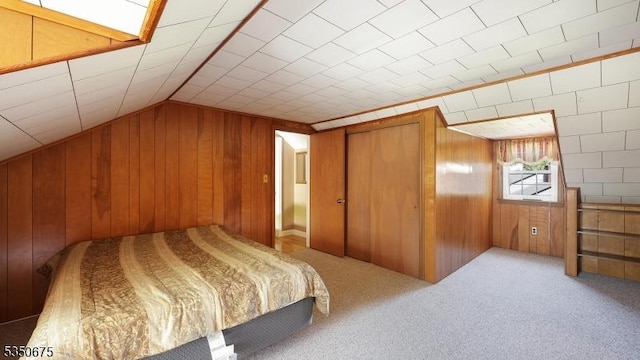 bedroom with wood walls, lofted ceiling, and carpet flooring