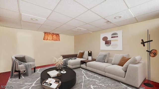 carpeted living area featuring a drop ceiling