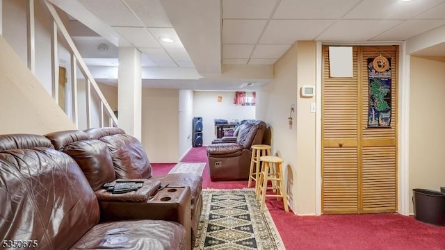 living area with carpet, a drop ceiling, and stairway