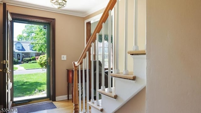 entrance foyer featuring stairs, ornamental molding, and wood finished floors