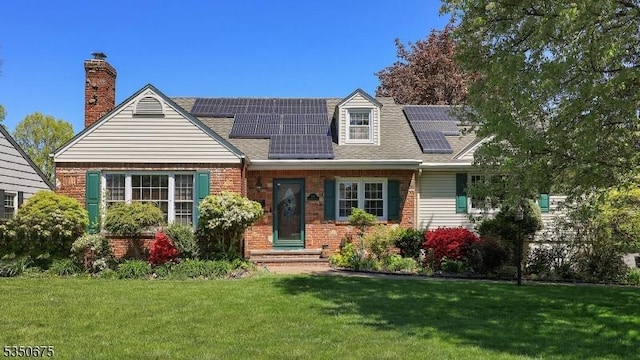cape cod home featuring a chimney, roof mounted solar panels, roof with shingles, and a front lawn