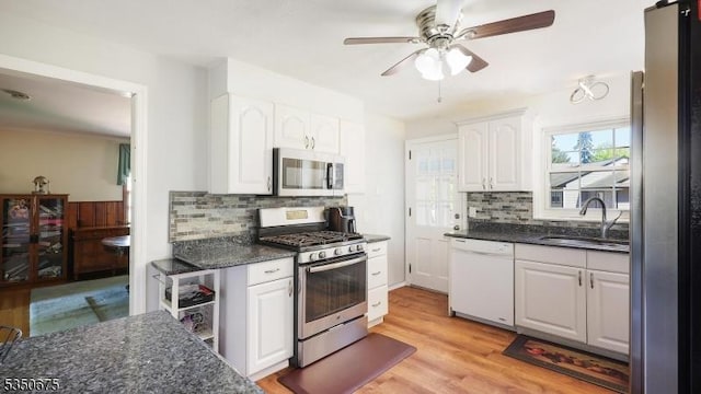 kitchen with a ceiling fan, white cabinets, a sink, backsplash, and stainless steel appliances