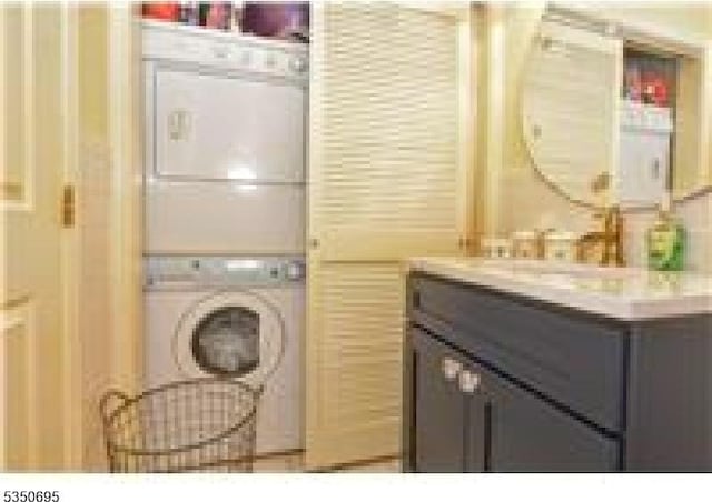 washroom featuring tile walls, stacked washer / dryer, and laundry area