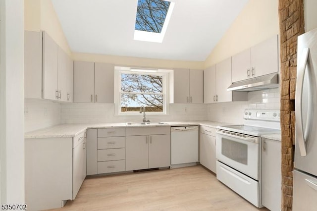kitchen featuring a sink, decorative backsplash, white appliances, and under cabinet range hood