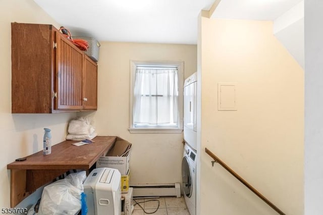 laundry area featuring stacked washing maching and dryer, a baseboard heating unit, cabinet space, and light tile patterned floors