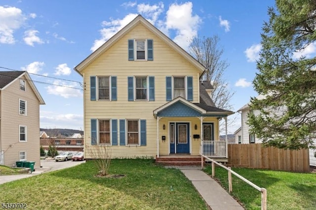 view of front of house featuring covered porch, a front yard, and fence