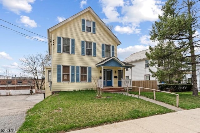 traditional-style house with a front lawn, fence, and covered porch