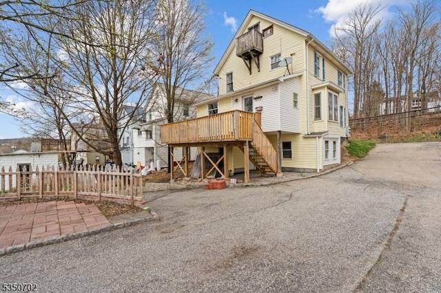 rear view of property featuring stairway, a deck, and fence