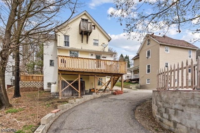 back of house with a wooden deck, aphalt driveway, and stairs