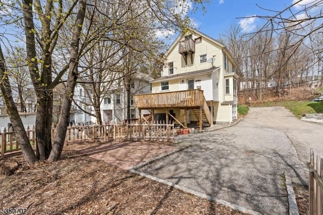 back of house featuring a deck, a gambrel roof, fence, and stairway