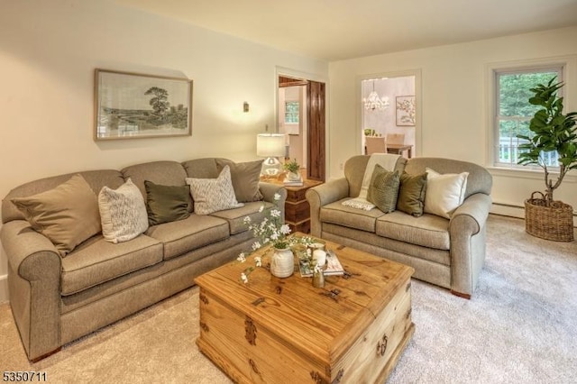 living area with light colored carpet, a baseboard radiator, and a chandelier