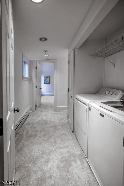 laundry area featuring independent washer and dryer, baseboard heating, light colored carpet, and baseboards