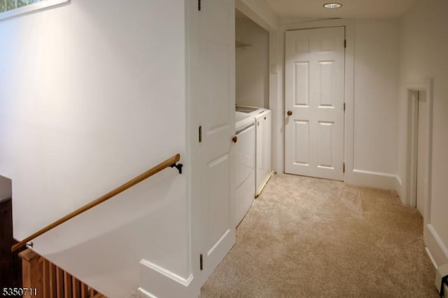 hallway with separate washer and dryer, light colored carpet, and an upstairs landing