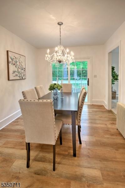 dining space featuring baseboards, a chandelier, wood finished floors, and radiator heating unit