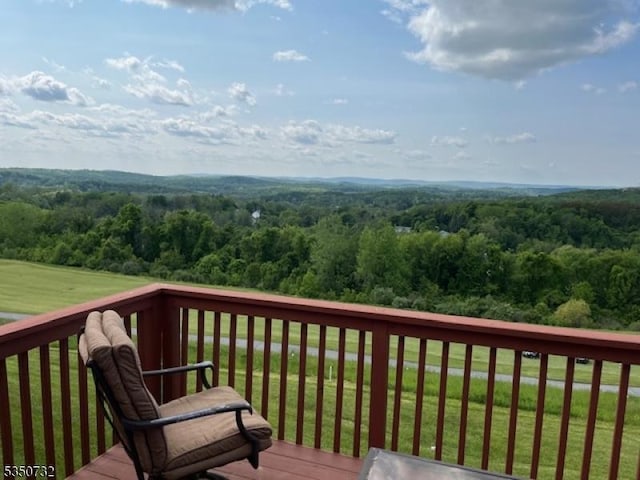 deck featuring a lawn and a wooded view