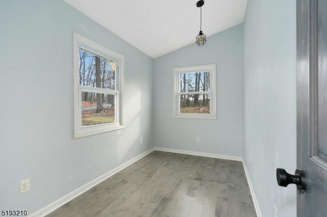 spare room with wood finished floors, vaulted ceiling, and baseboards