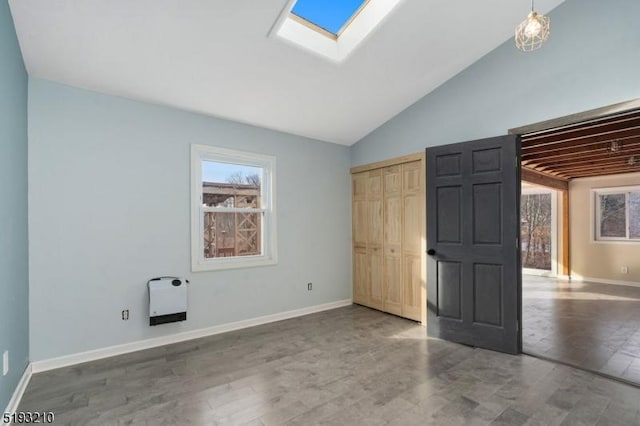 unfurnished bedroom with a closet, baseboards, and vaulted ceiling with skylight