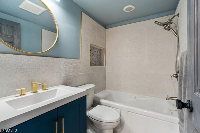 bathroom with bathing tub / shower combination, tile walls, toilet, vanity, and visible vents