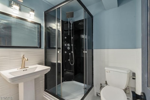 full bathroom featuring toilet, a stall shower, tile walls, and a sink