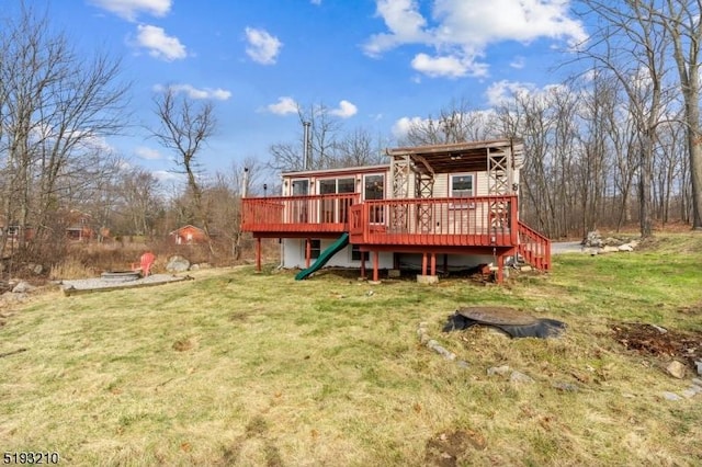 rear view of house featuring a wooden deck and a yard