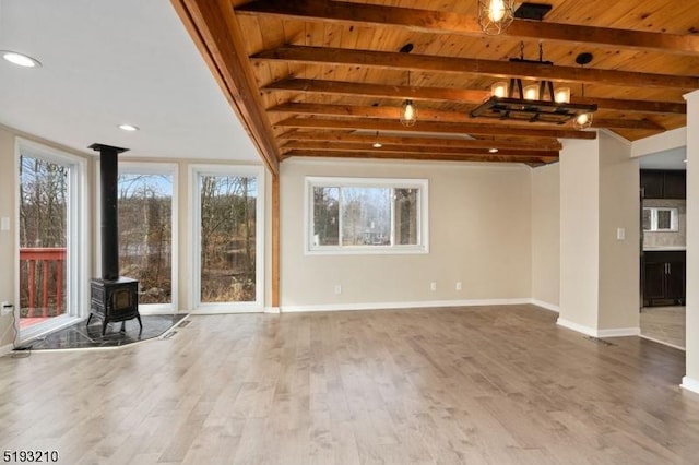 unfurnished living room featuring a wood stove, wood finished floors, wood ceiling, and plenty of natural light