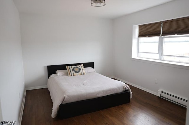 bedroom with a baseboard radiator, baseboards, and wood finished floors