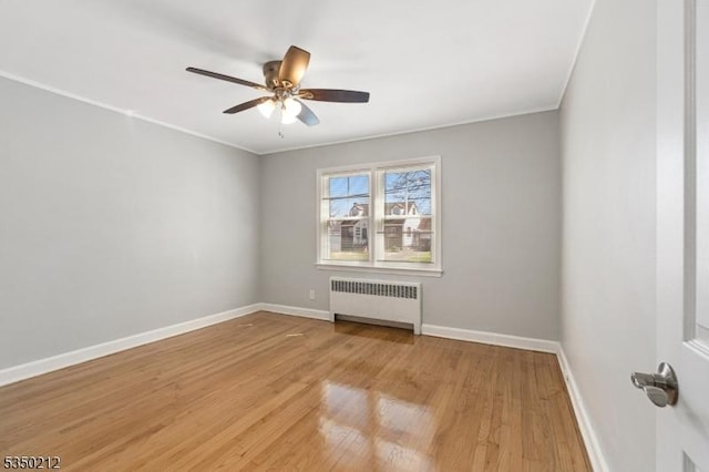 unfurnished room featuring crown molding, radiator, ceiling fan, light wood-style flooring, and baseboards