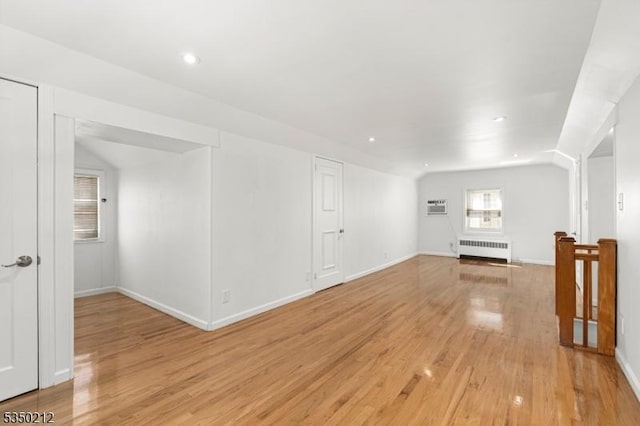 unfurnished living room with light wood-style floors, radiator, recessed lighting, an AC wall unit, and baseboards