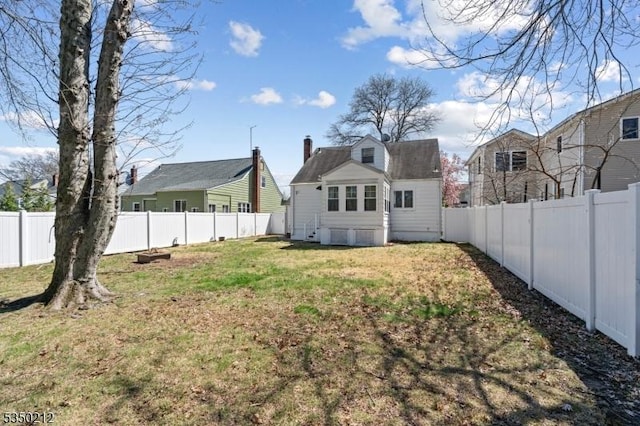 back of property with a fenced backyard and a lawn