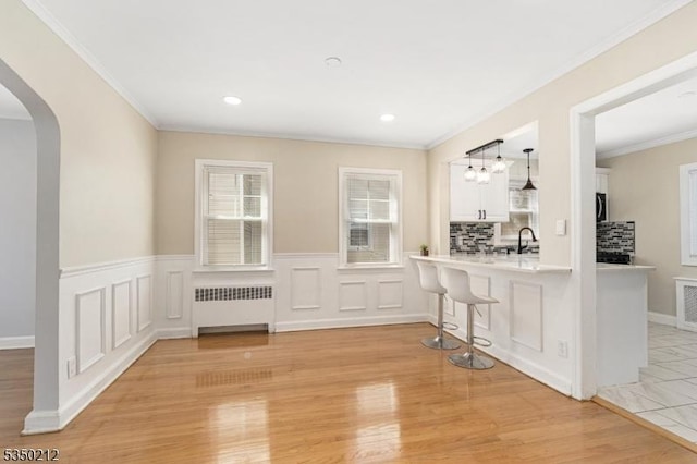 interior space with radiator heating unit, arched walkways, a sink, and a wealth of natural light